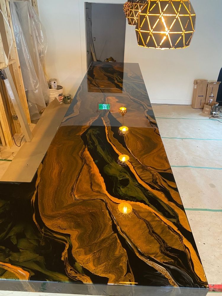 Un long comptoir noir et or dans une pièce avec une suspension suspendue au plafond.