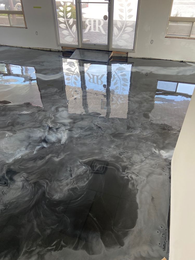 Un salon avec un sol métallique brillant et un reflet d'un bâtiment dans le sol.