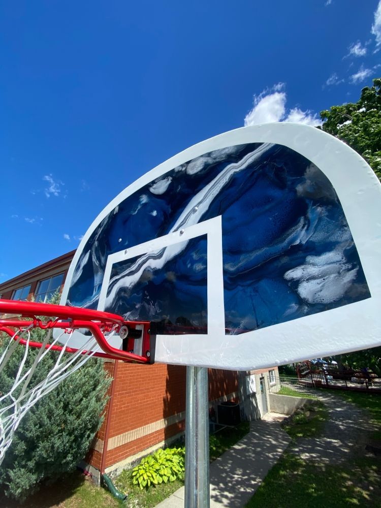Un panier de basket est placé devant un bâtiment en briques.