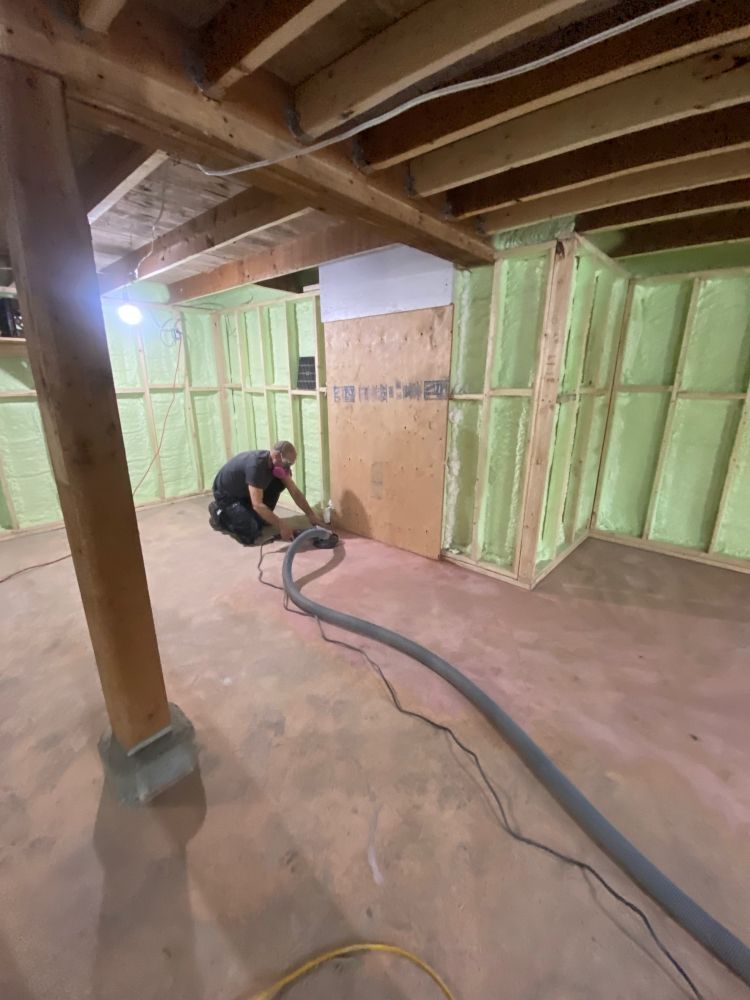 Un homme utilise un aspirateur dans un sous-sol.