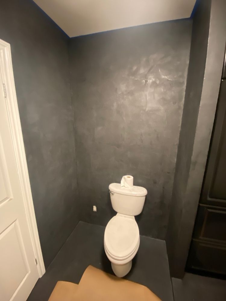 Une salle de bain avec toilettes et un mur gris