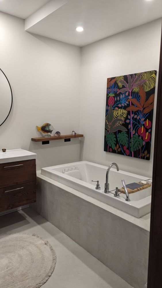 Une salle de bain avec baignoire, lavabo, miroir et tableau au mur.