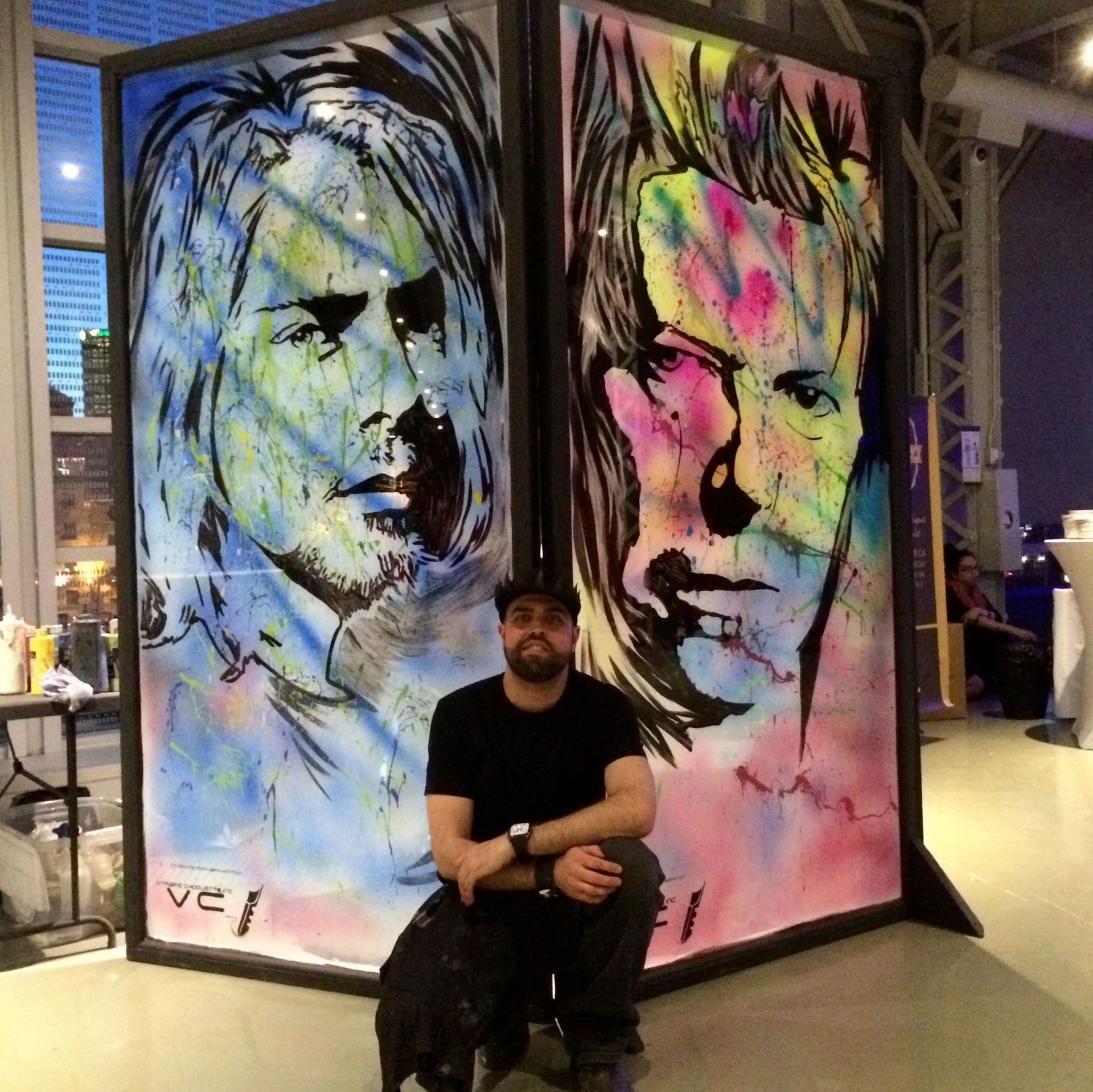 Un homme assis devant un tableau sur lequel est écrit vel