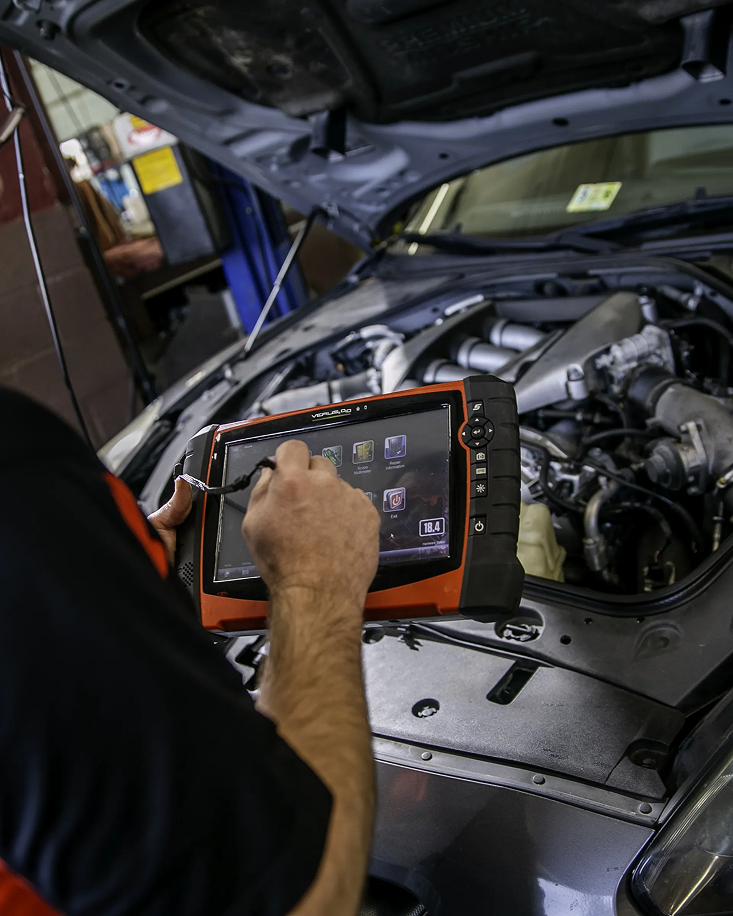 A man is using a tablet to look at the engine of a car | Yes! Automotive