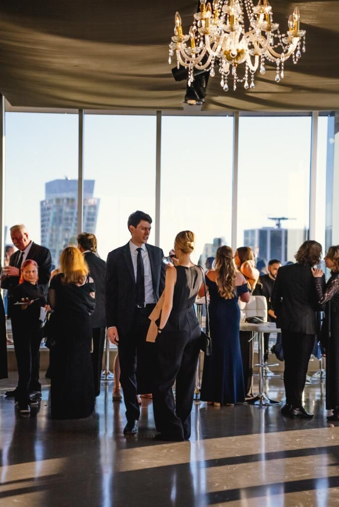 A group of people are standing in a room with a chandelier.