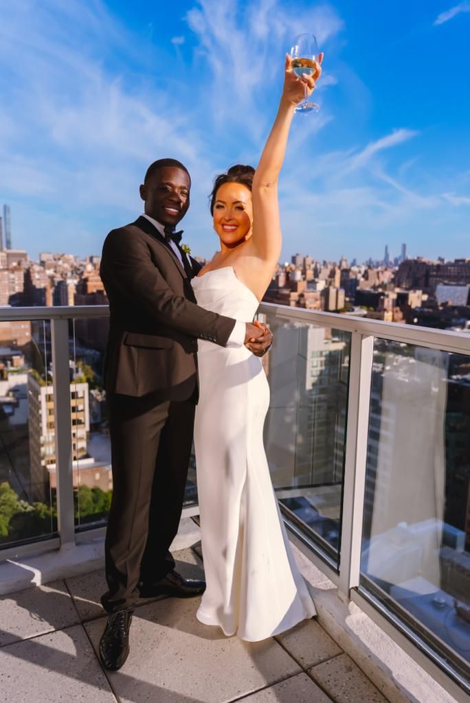 A bride and groom are posing for a picture on a balcony.