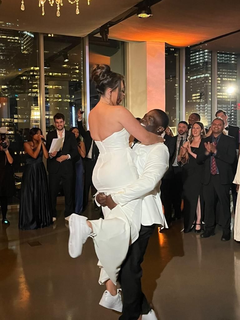 A man is holding a woman in his arms while they dance at a wedding reception.