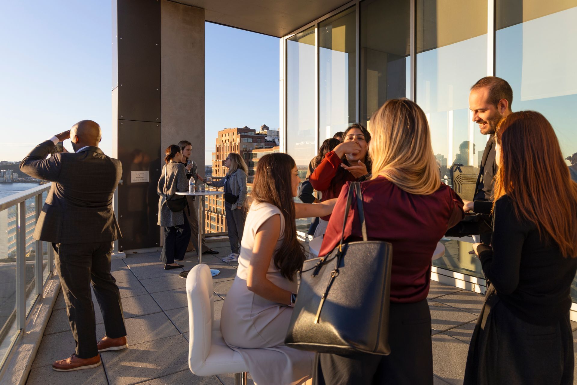 Rooftop party at night with city skyline in background, people mingling, Christmas lights.