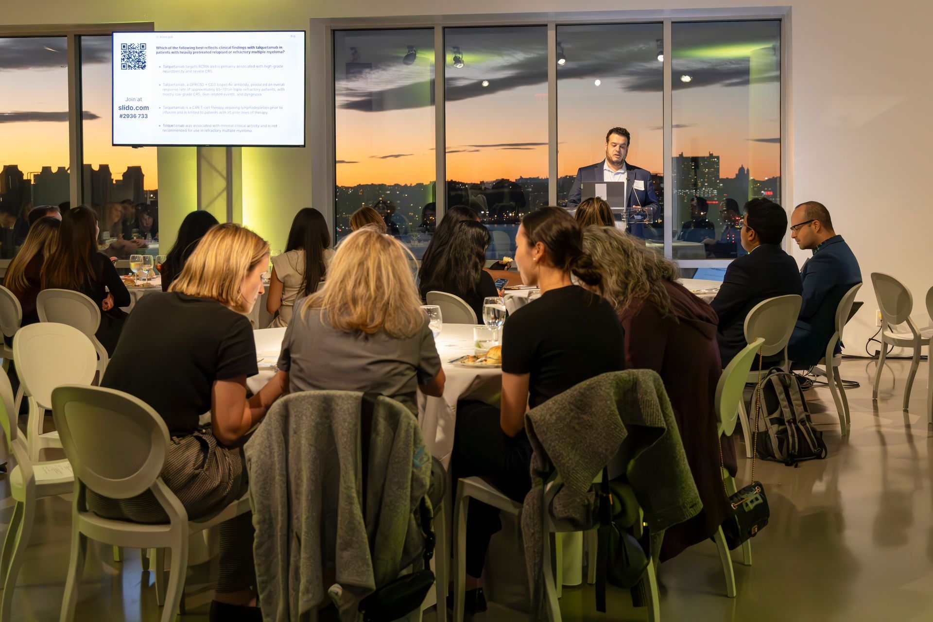 Nighttime view of a city skyline with illuminated skyscrapers under a dark blue sky.