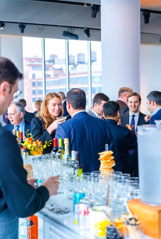 A group of people are standing around a bar at a party.