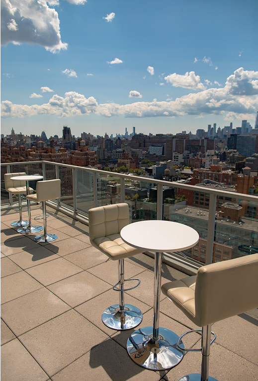 A patio with tables and chairs with a view of the city