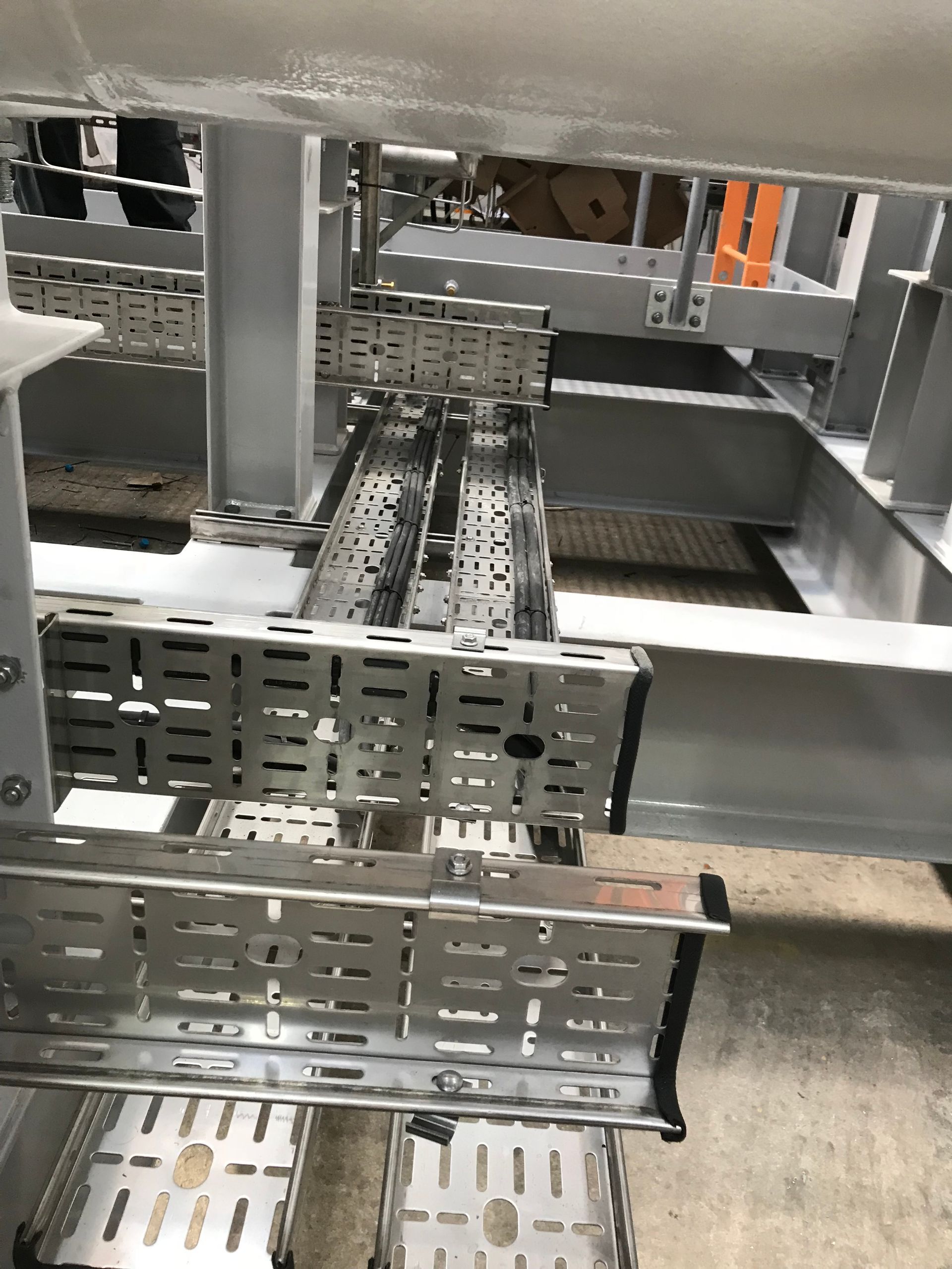 A close-up of perforated steel cable trays arranged on a metal framework in an industrial or construction setting.