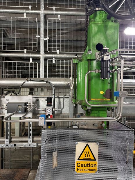 A stainless steel industrial instrument panel with pressure gauges, valves, tubing, and a flow meter mounted on a wall.