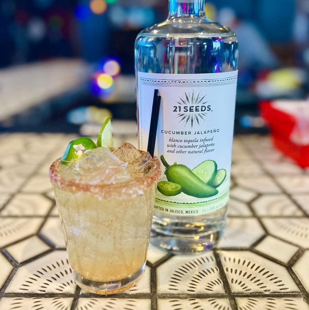 A bottle of 21 seeds vodka next to a glass of vodka