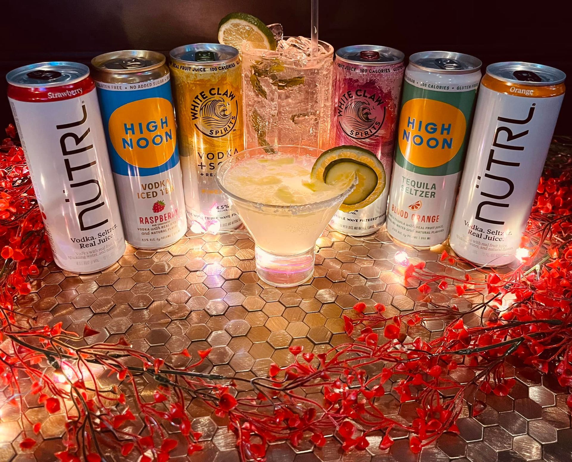 A variety of drinks are sitting on a table next to cans of energy drinks.