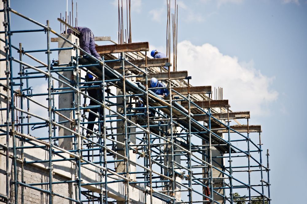 A Group of Construction Workers Are Working on a Building With Scaffolding — Byron Bay Scaffold in Kinvara, NSW