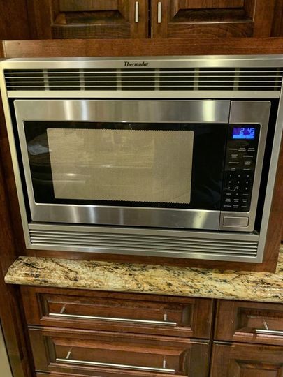 A stainless steel microwave oven is built into the wall of a kitchen.