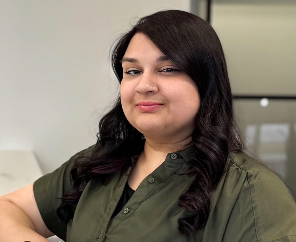 A woman in a green shirt is smiling for the camera.