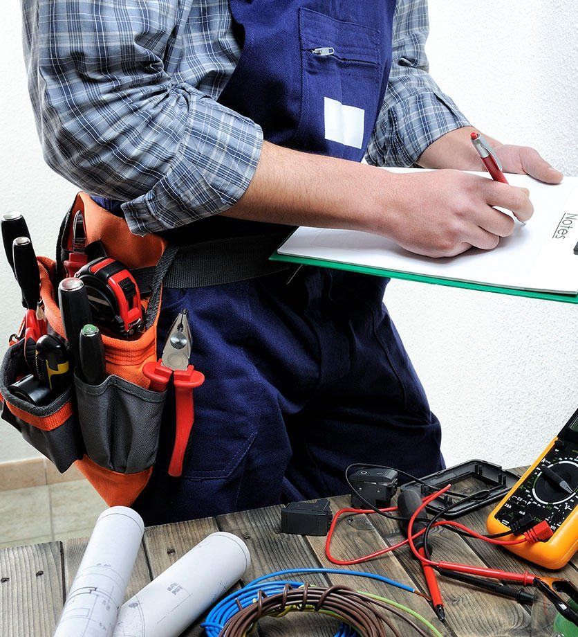A man with a tool belt around his waist is writing on a clipboard