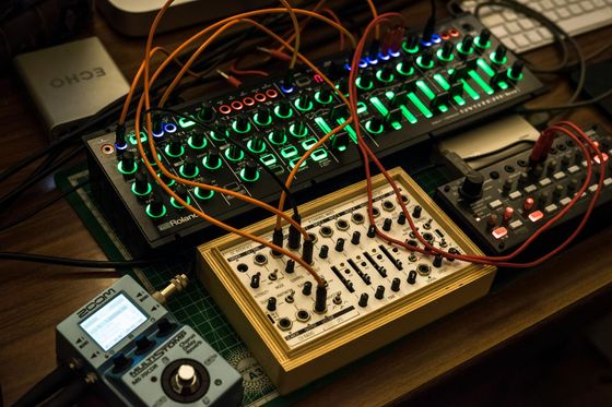 A bunch of electronic devices are on a table including a keyboard