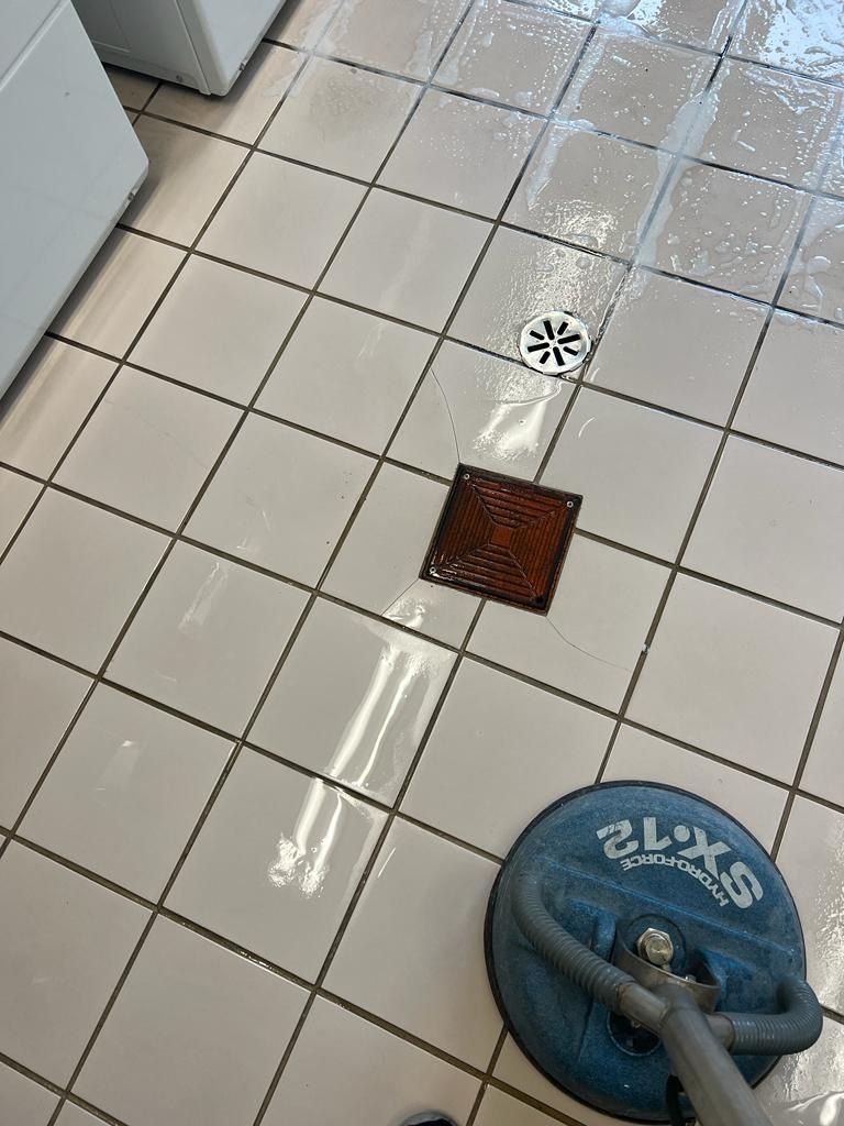 A person is cleaning a tiled floor with a machine.