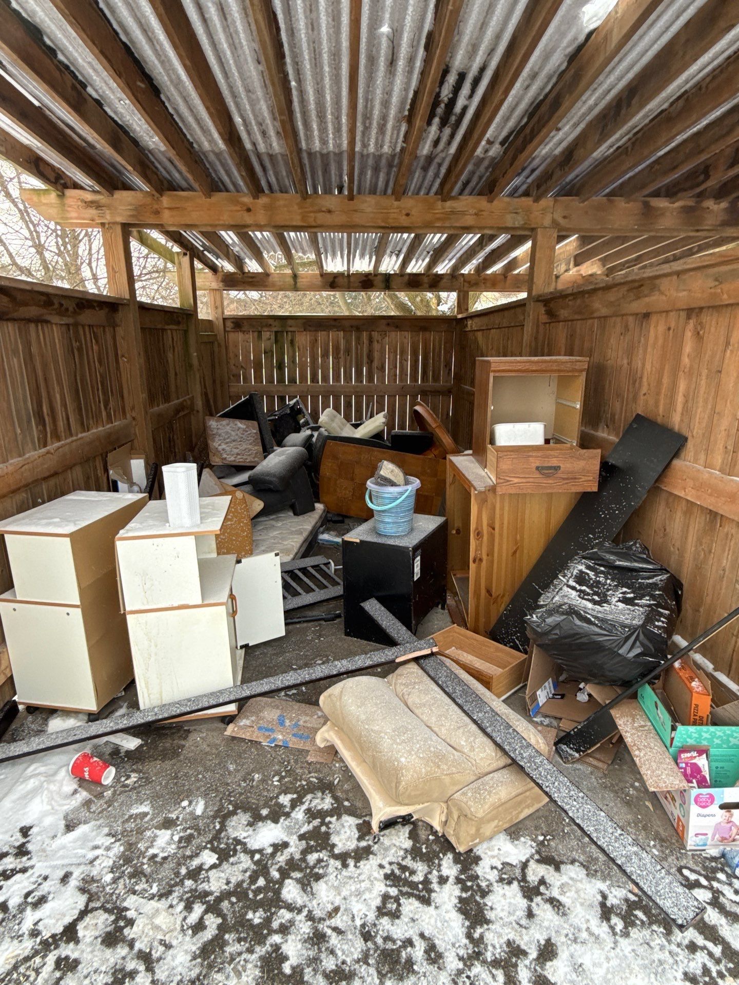 A wooden shed filled with lots of trash and junk.