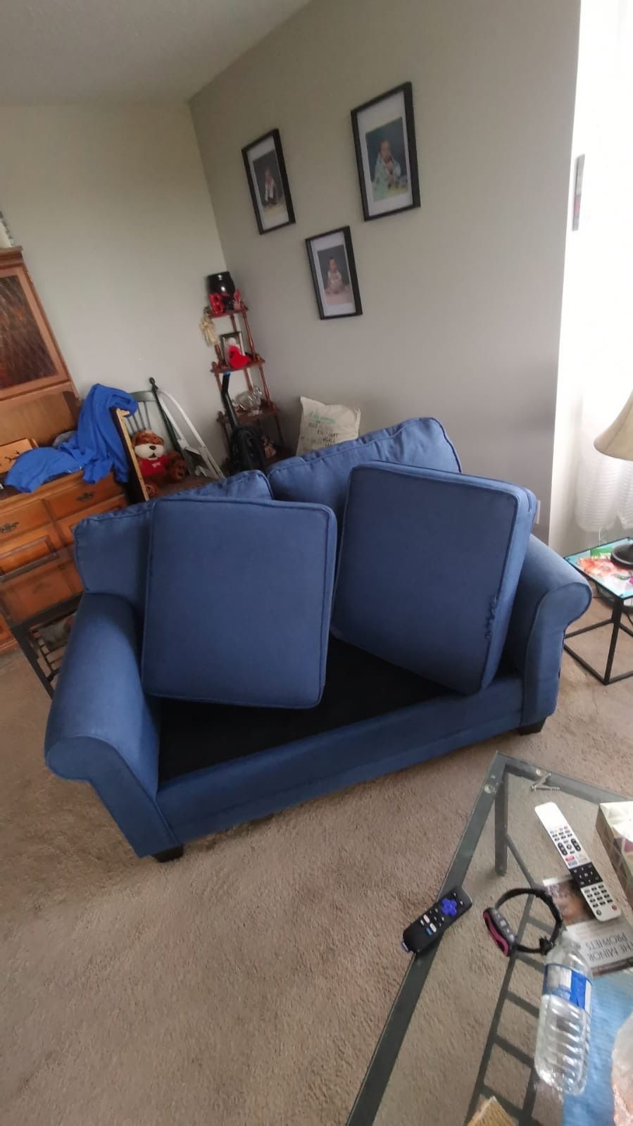 A blue couch is sitting in a living room next to a glass table.