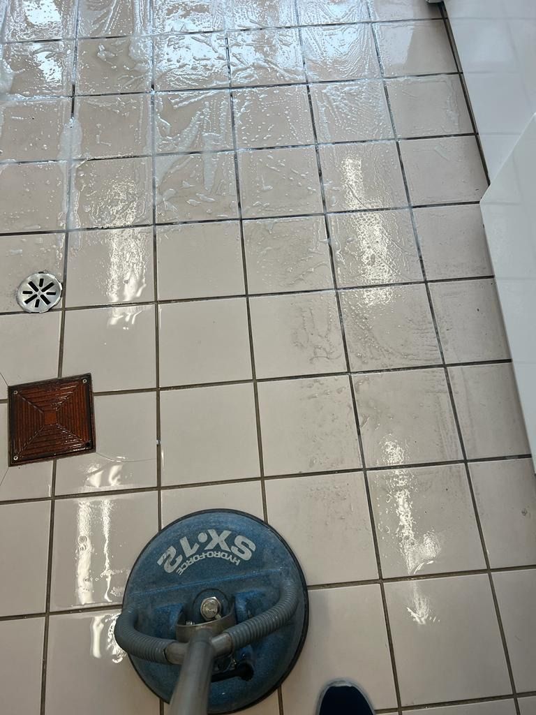 A person is cleaning a tiled floor with a machine.