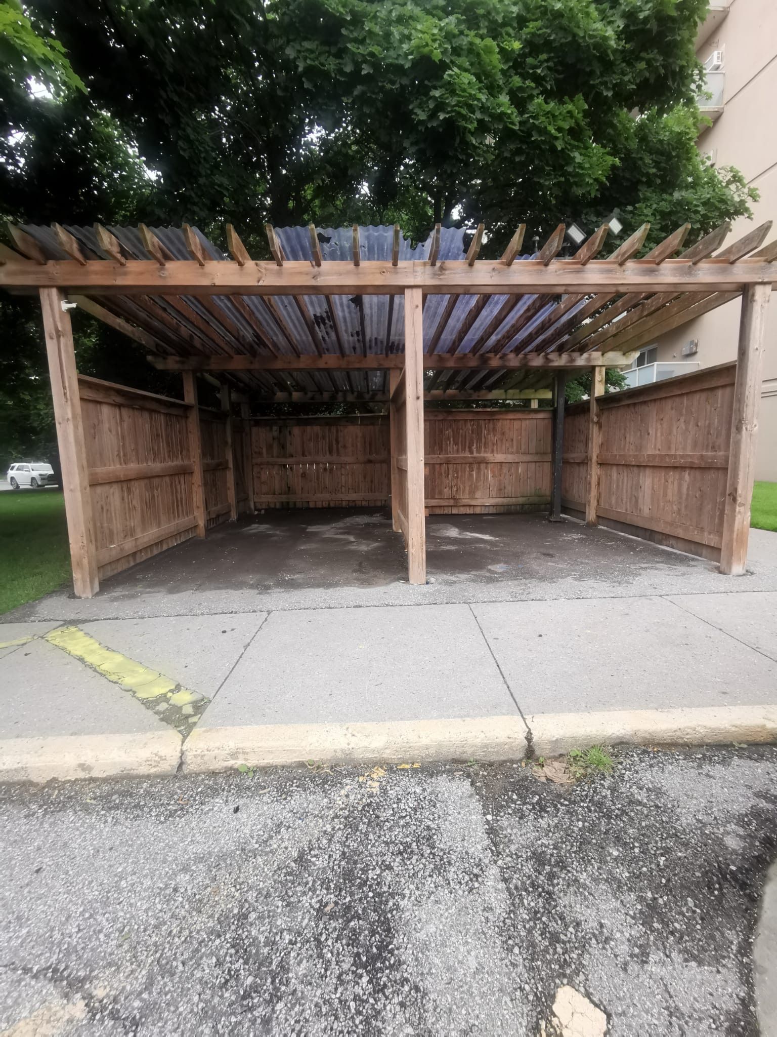 A wooden pergola is sitting on the side of the road.