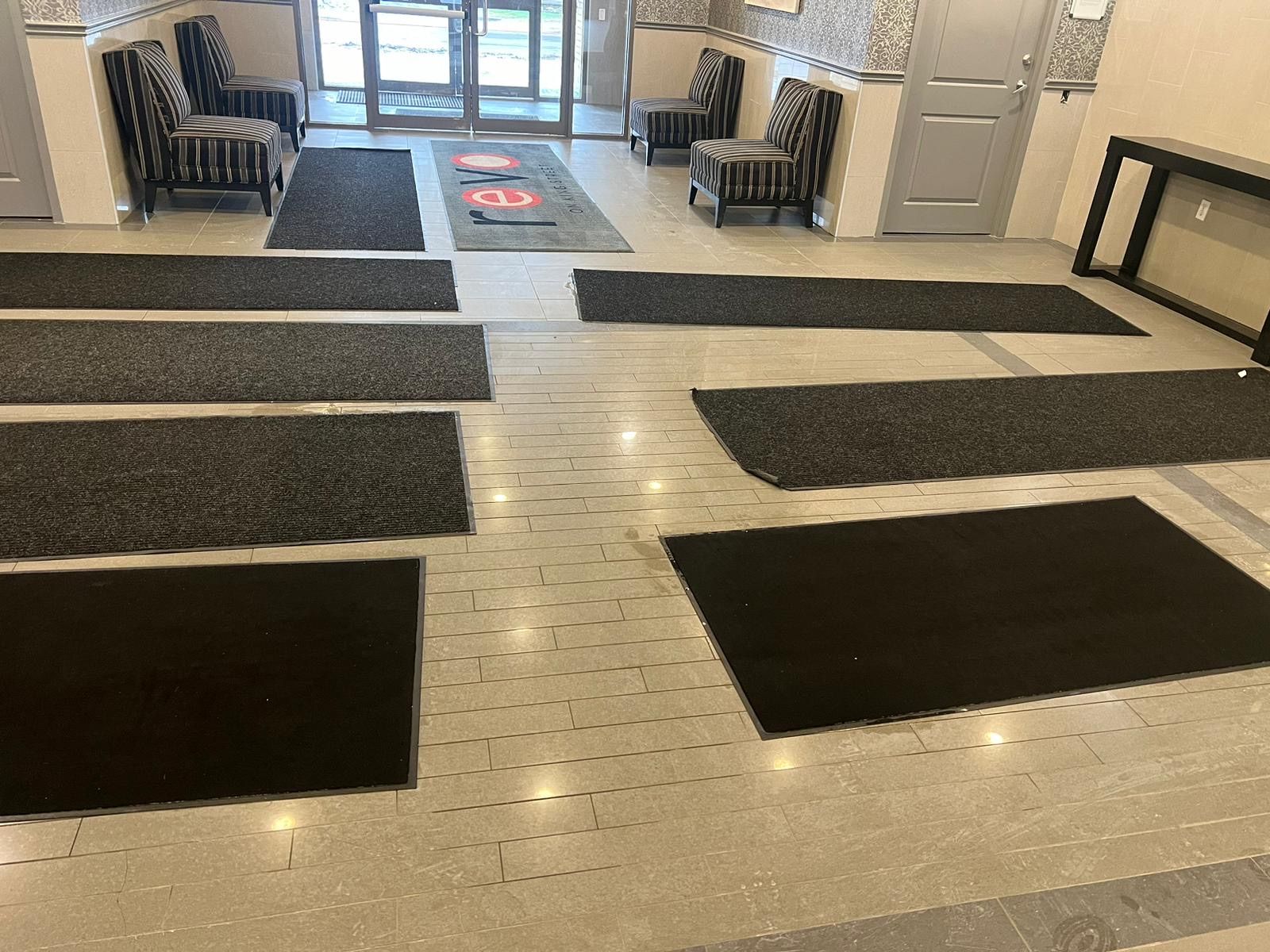 A lobby with a lot of black mats on the floor.