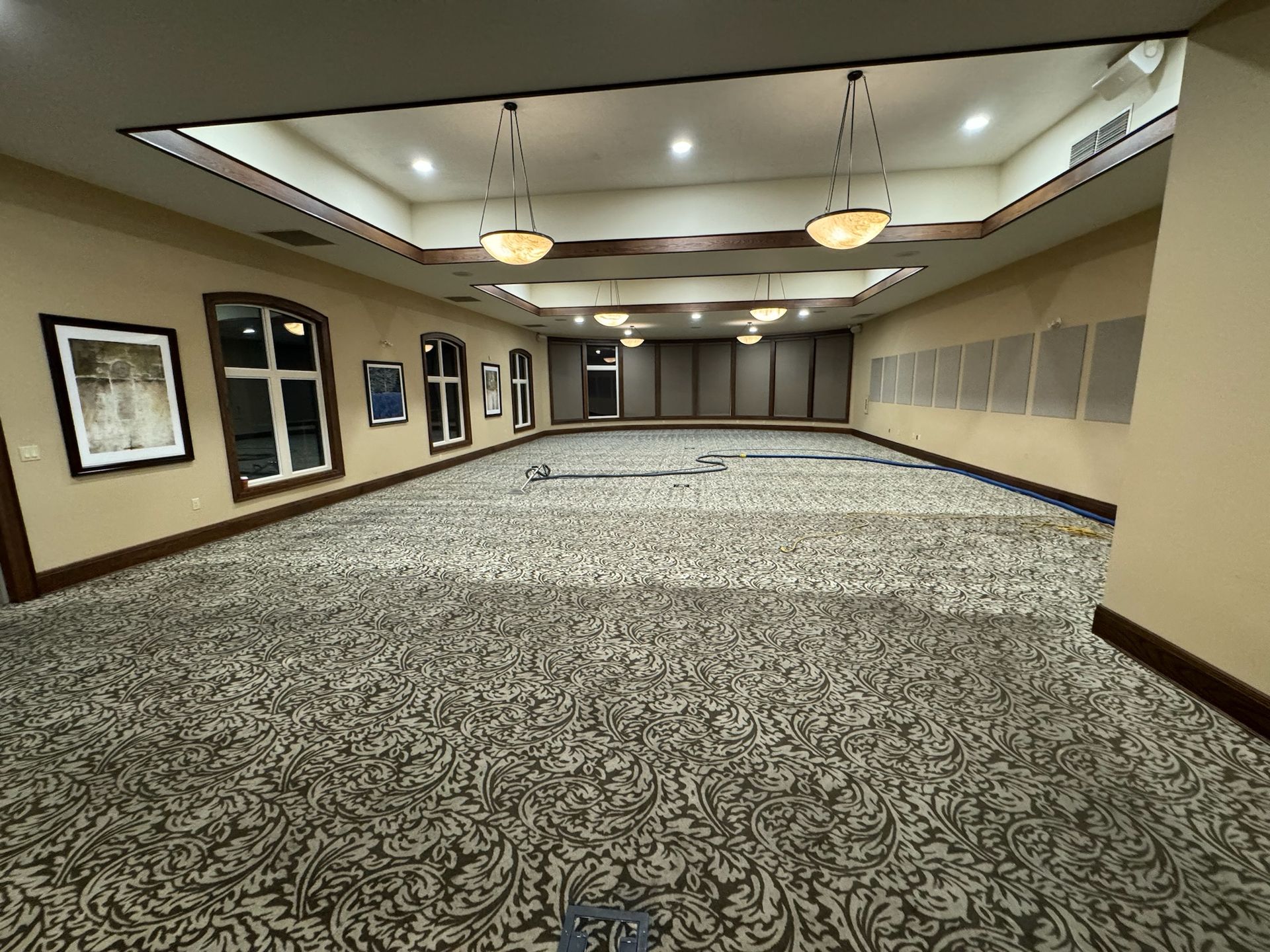 A large empty room with a carpeted floor and a ceiling.