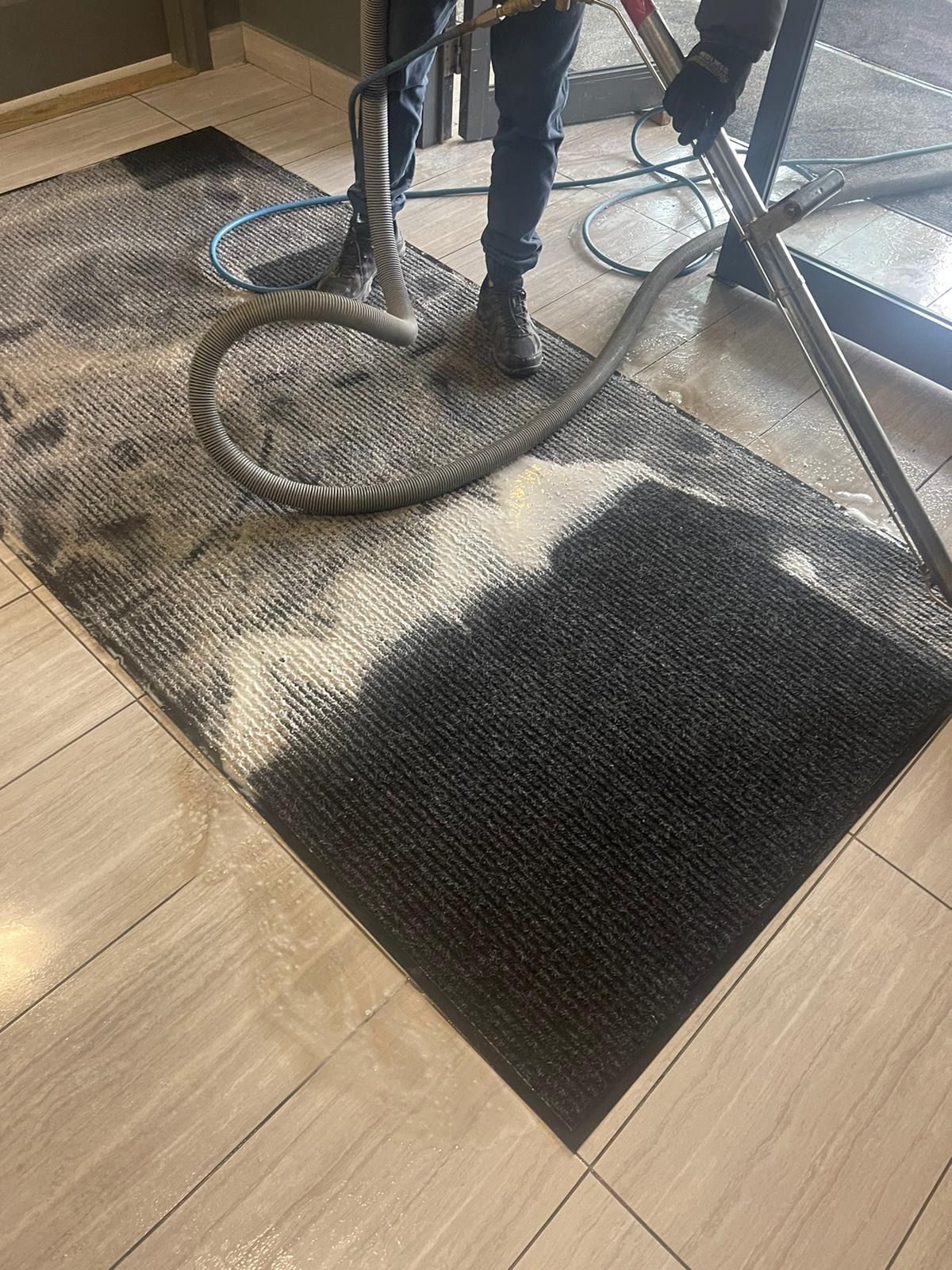 A man is cleaning a rug with a machine in a room.