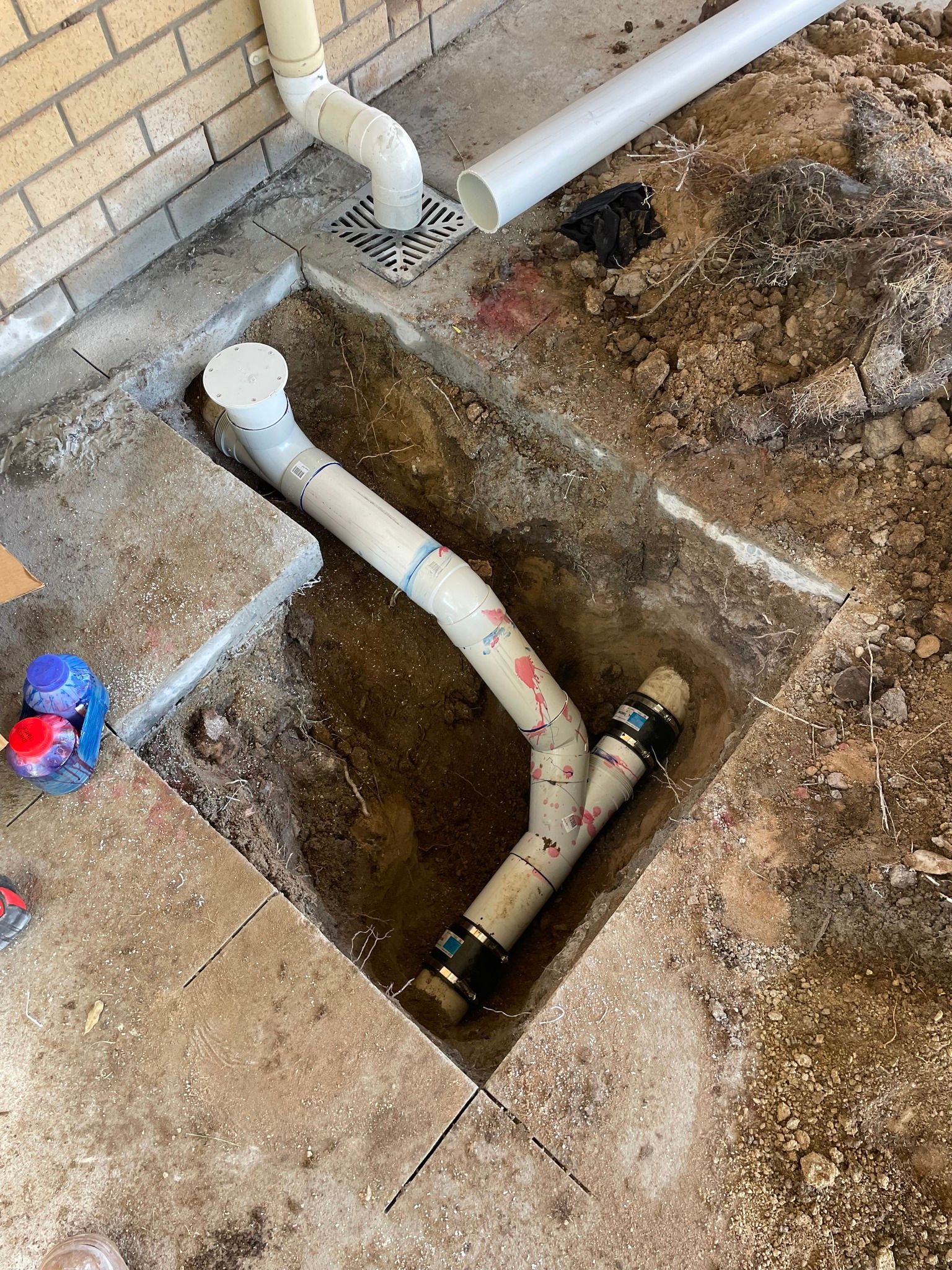 A White Pvc Sewer Cleanout Pipe Installed In An Outdoor Trench — Mates Plumbing and Gas in Lammermoor, QLD