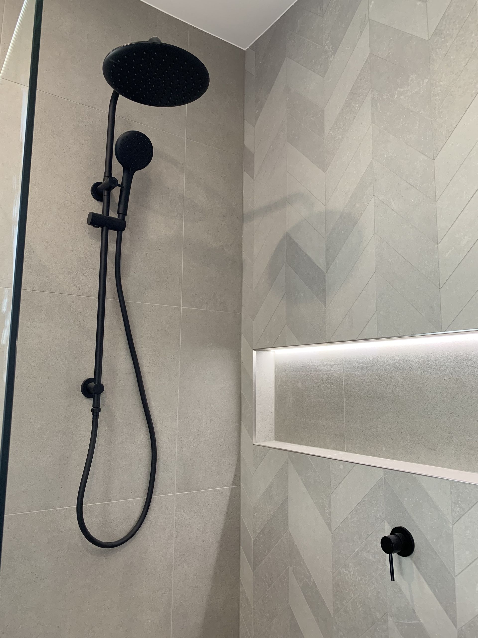 A Tiled Shower Wall With a Horizontal Strip of Mosaic Tiles, Backlighting — Mates Plumbing and Gas in Lammermoor, QLD