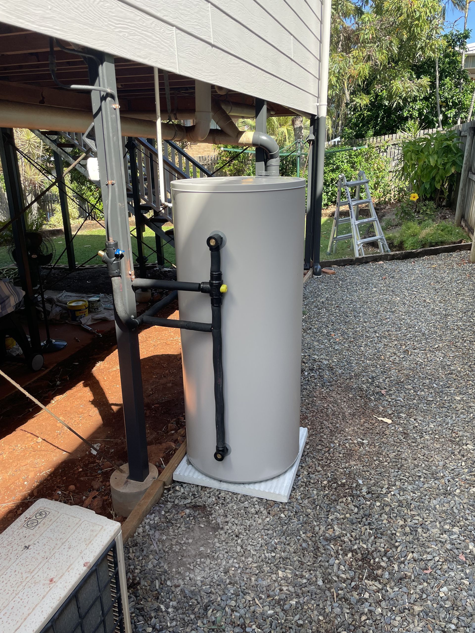 A Silver Tankless Gas Water Heater Mounted on an Exterior Brick Wall — Mates Plumbing and Gas in Lammermoor, QLD