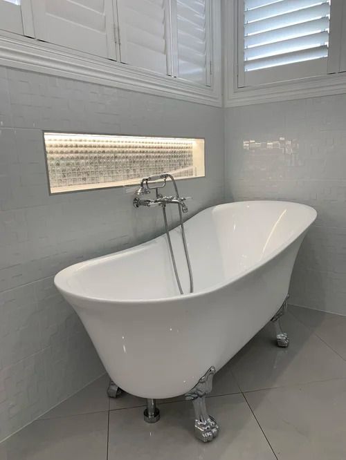 A White Clawfoot Bathtub With Chrome Fixtures Sits Against a Gray Tiled Wall — Mates Plumbing and Gas in Lammermoor, QLD