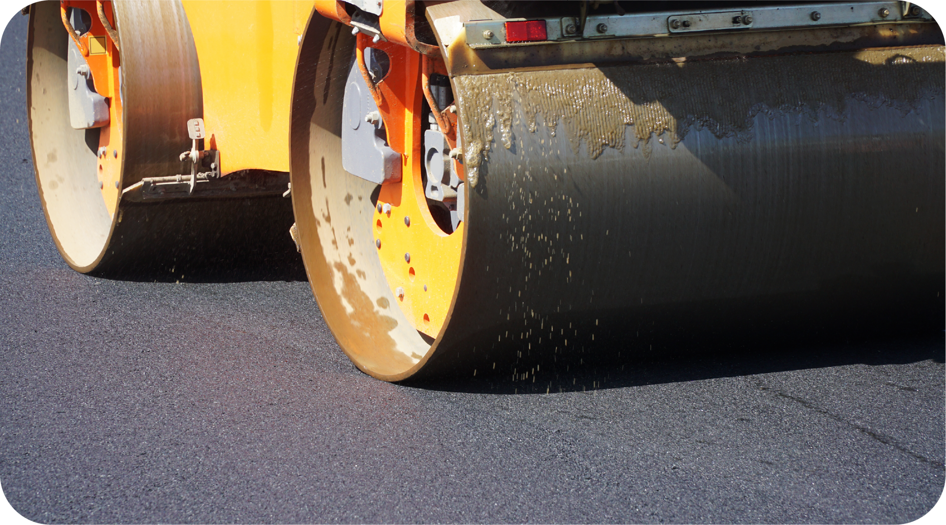 A yellow roller is rolling asphalt on a road.