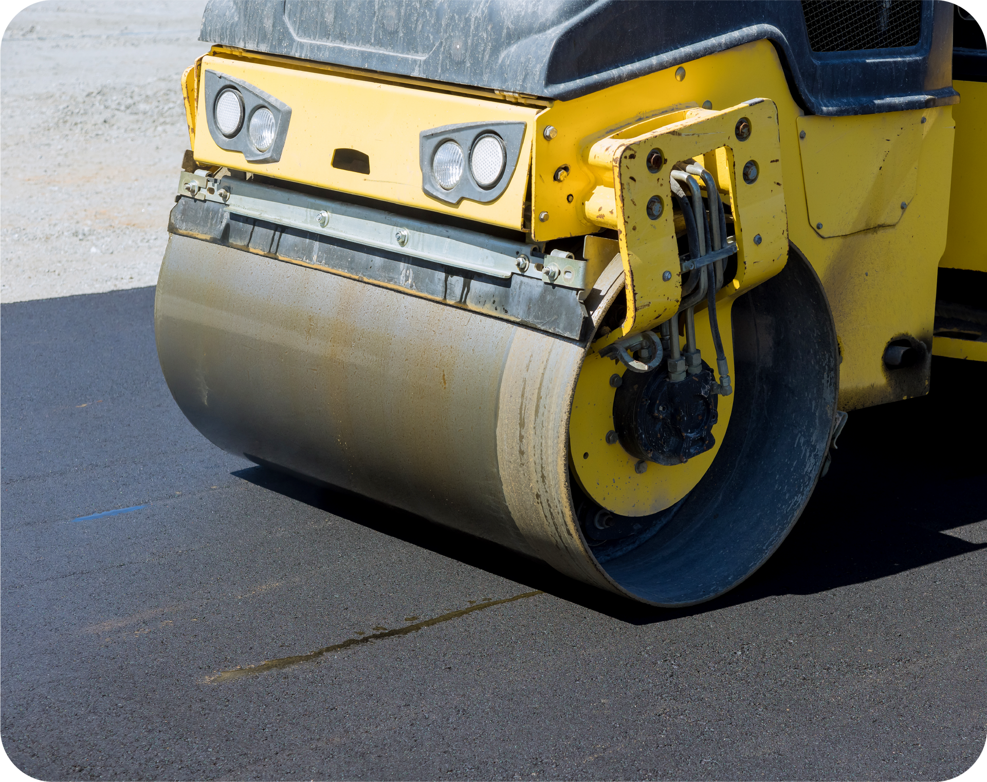 A yellow roller is rolling asphalt on a road
