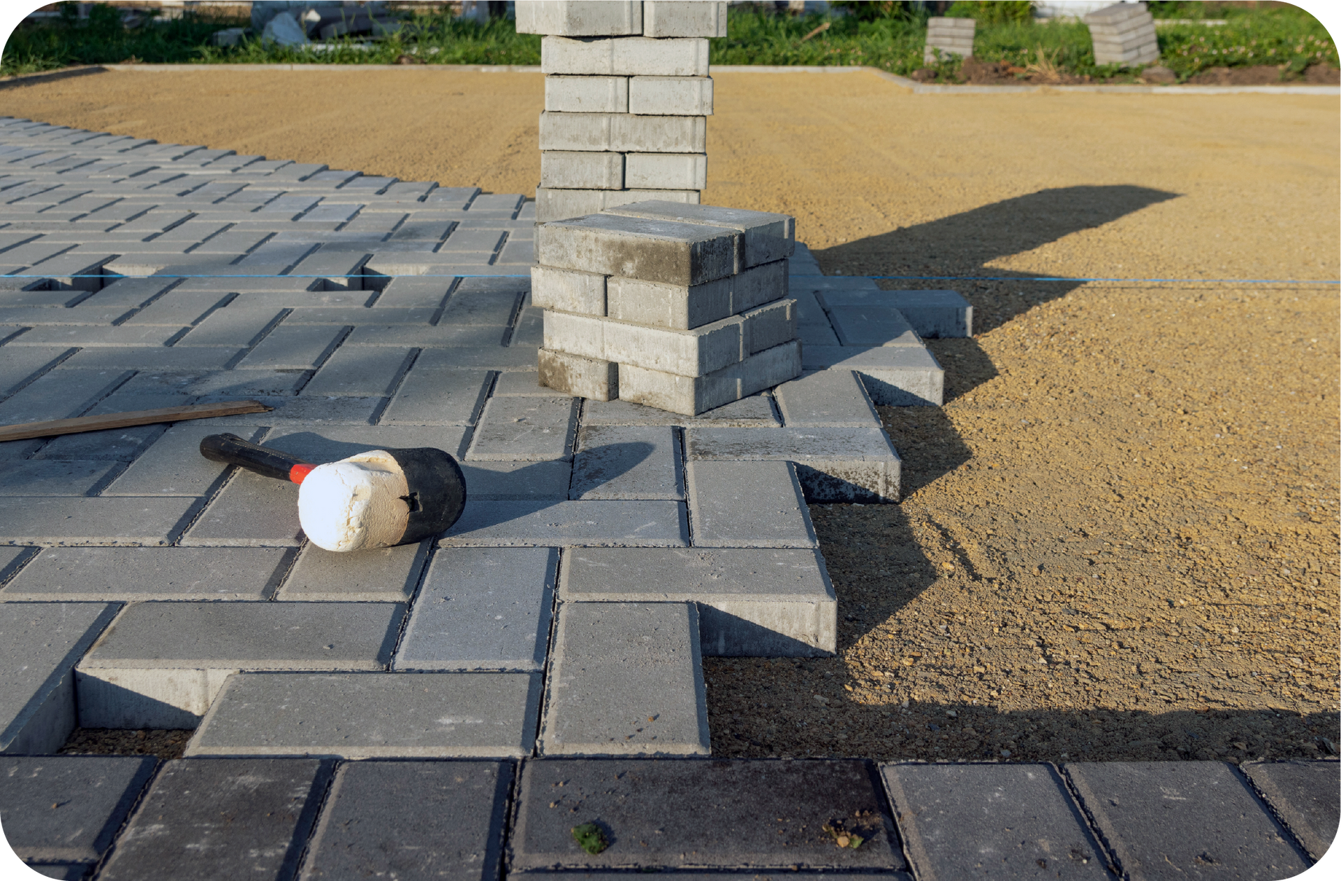 A hammer is laying on the ground next to a pile of bricks.