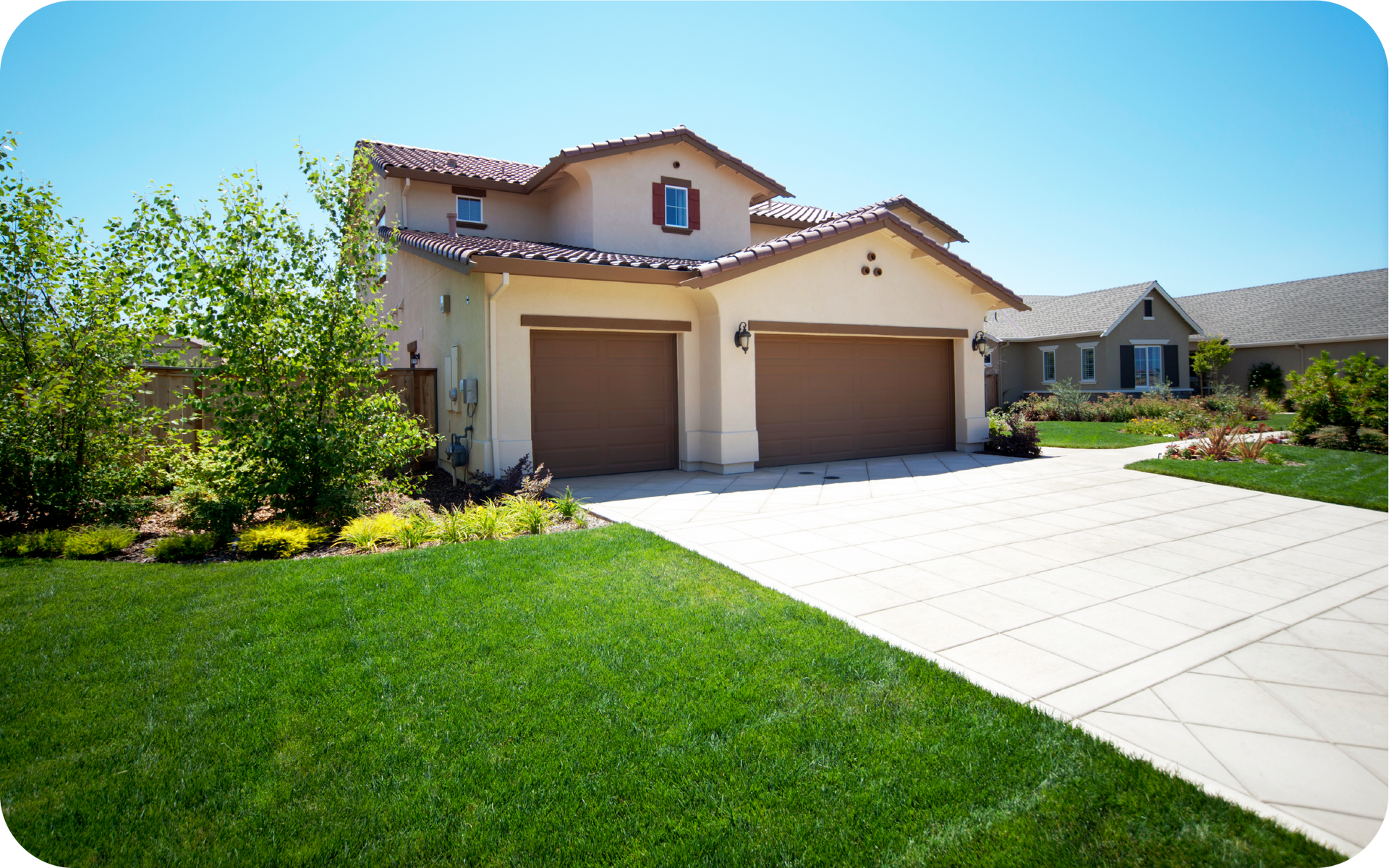 A large house with two garage doors and a driveway leading to it.