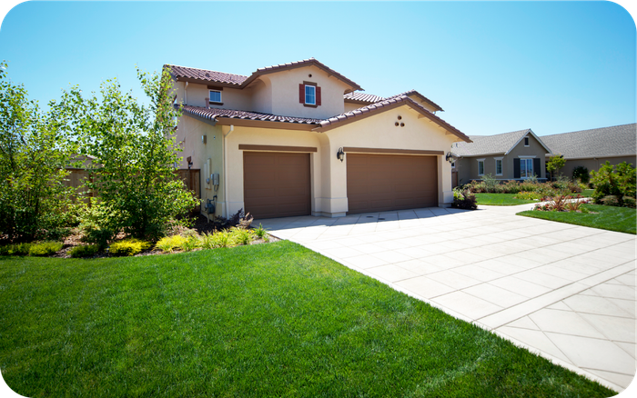 A large house with two garage doors and a driveway leading to it.