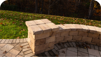 A brick wall surrounds a patio with trees in the background