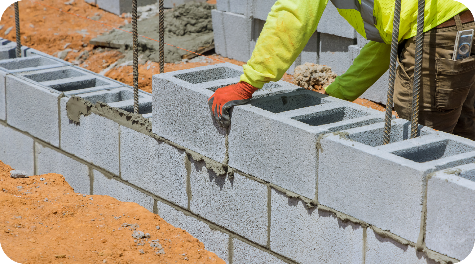 A construction worker is laying concrete blocks on a construction site.
