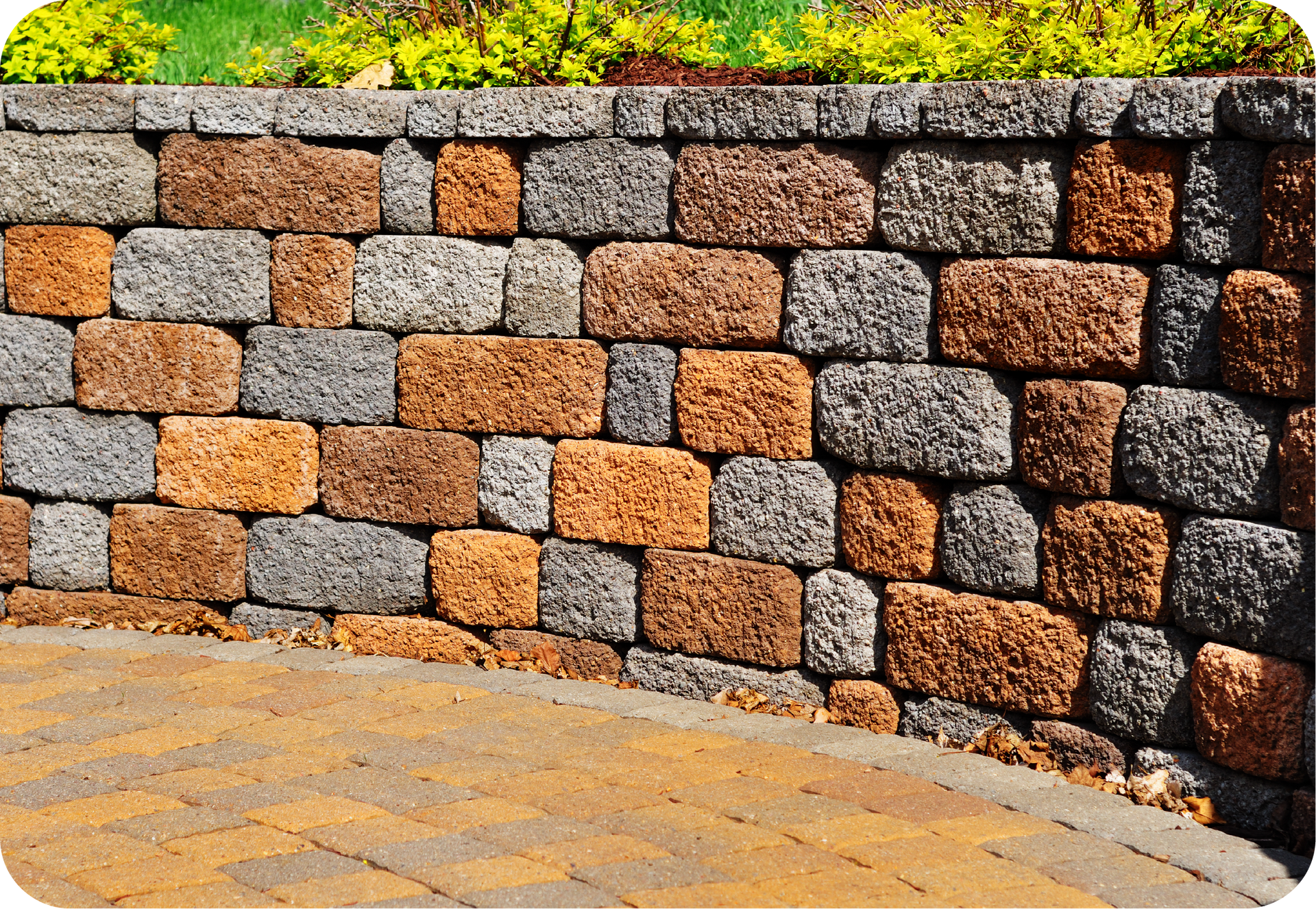 A brick wall with a brick walkway in front of it.