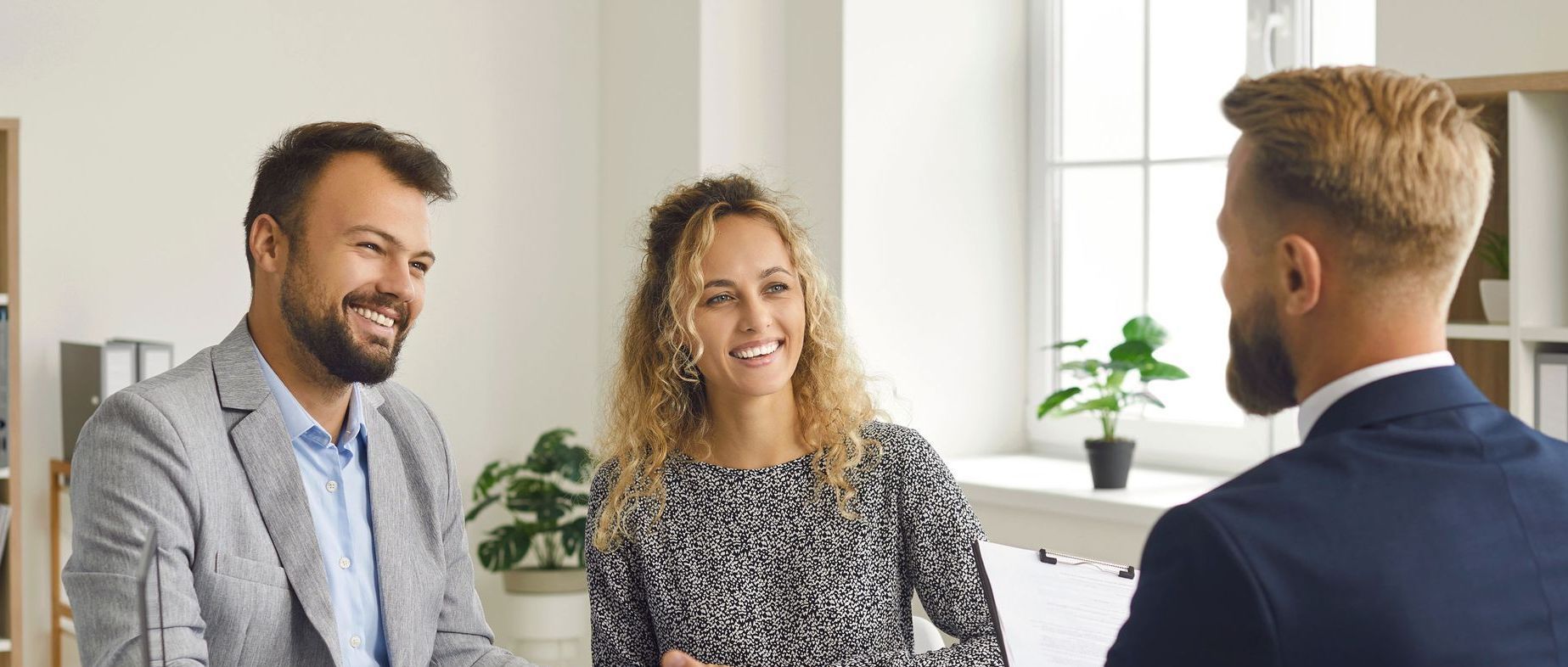A man and a woman are talking to a real estate agent in a living room.