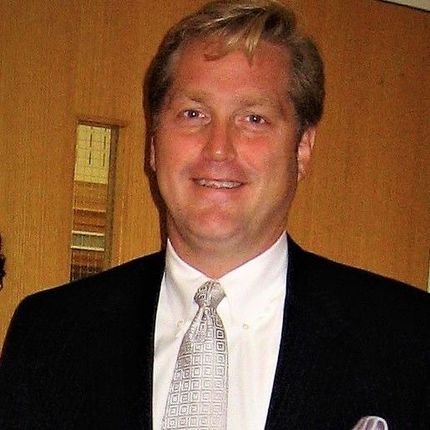 A man in a suit and tie is smiling for the camera