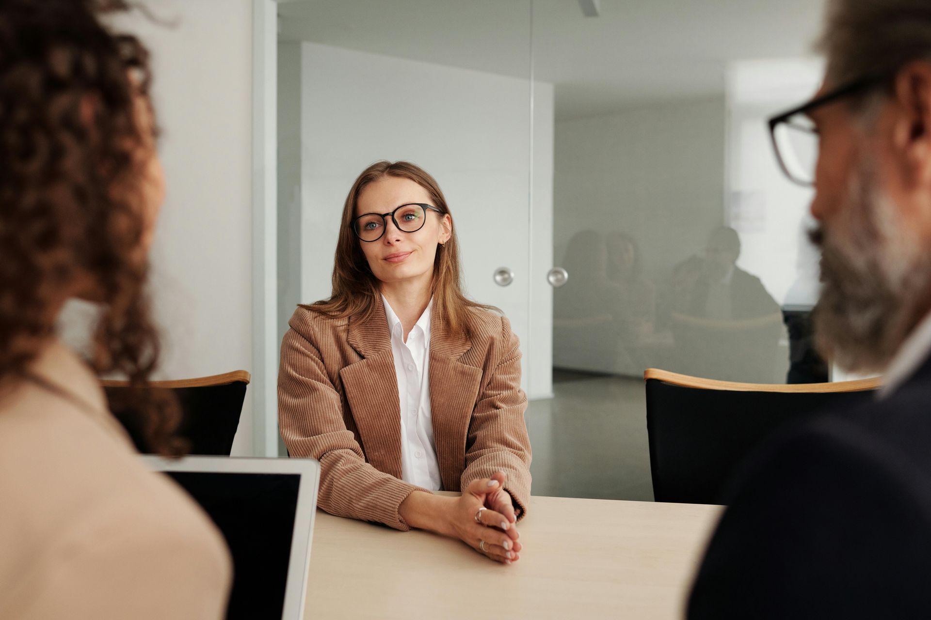 A woman is sitting at a table having a job interview with two men.