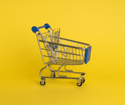 a small shopping cart with a blue handle on a yellow background .