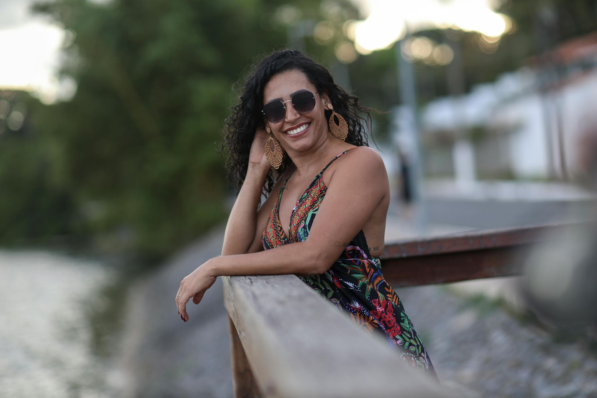 A woman wearing sunglasses is leaning on a wooden railing.