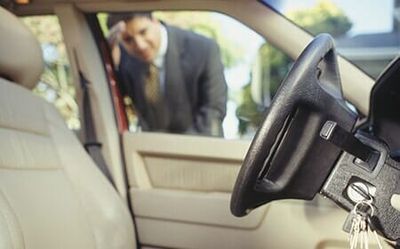 Businessman looking through window at keys locked in car — Locksmith in Des Moines, IA